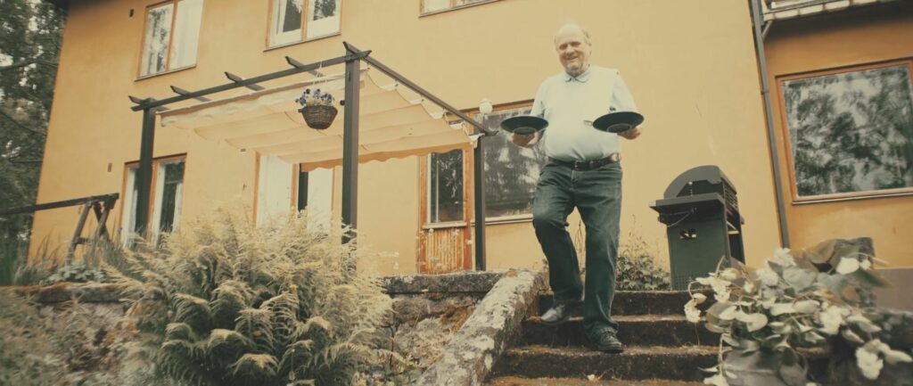 Vanhempi mies kauluspaidassa kävelee portaita alas kannatellen kummassakin kädessä lautasta.