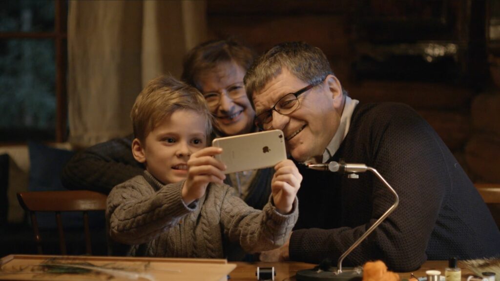 Nuori poika ottaa iphone puhelimella selfie-kuvaa itsestään ja kahdesta vanhemmasta henkilöstä.