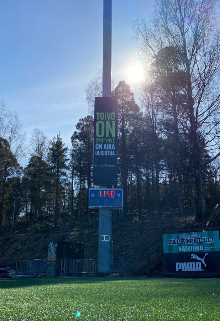 Kotkan Energian mainoskyltti tolpassa, metsän vieressä.